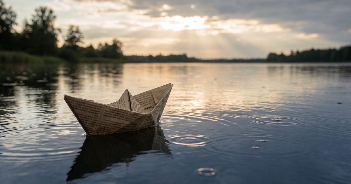 Paper boat made from newspaper floating on a calm lake at dusk — on the weight of constant rejection
